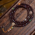 Cinnabar star moon bodhi 108 mala coiled on dark wood showing full layout with all charms