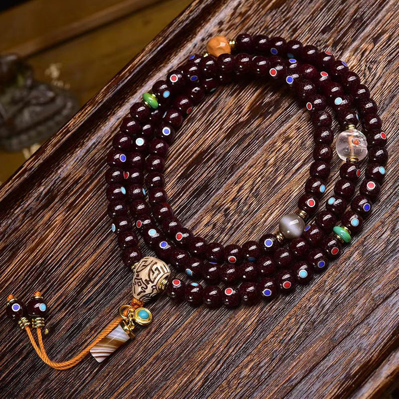 Cinnabar star moon bodhi 108 mala coiled on dark wood showing full layout with all charms