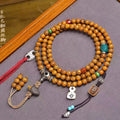 Vintage cracked star moon bodhi 108 mala coiled on grey surface with agate spacers, silver skull guru bead and red tassel