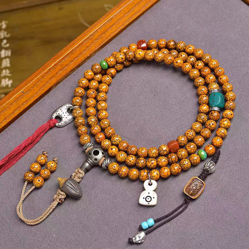 Vintage cracked star moon bodhi 108 mala coiled on grey surface with agate spacers, silver skull guru bead and red tassel