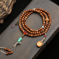 Vintage cocos 108 mala laid in circle on stone surface showing agate guru bead and turquoise horse head pendant