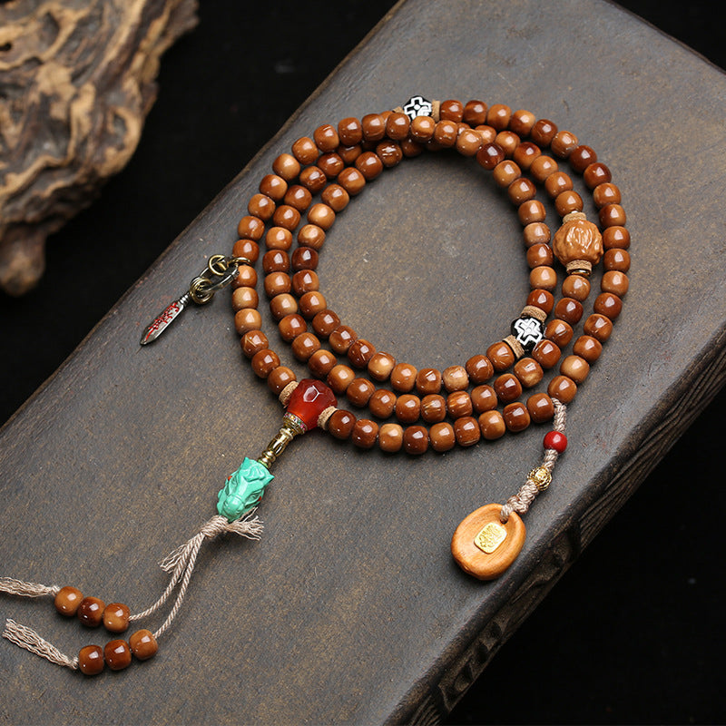 Vintage cocos 108 mala laid in circle on stone surface showing agate guru bead and turquoise horse head pendant