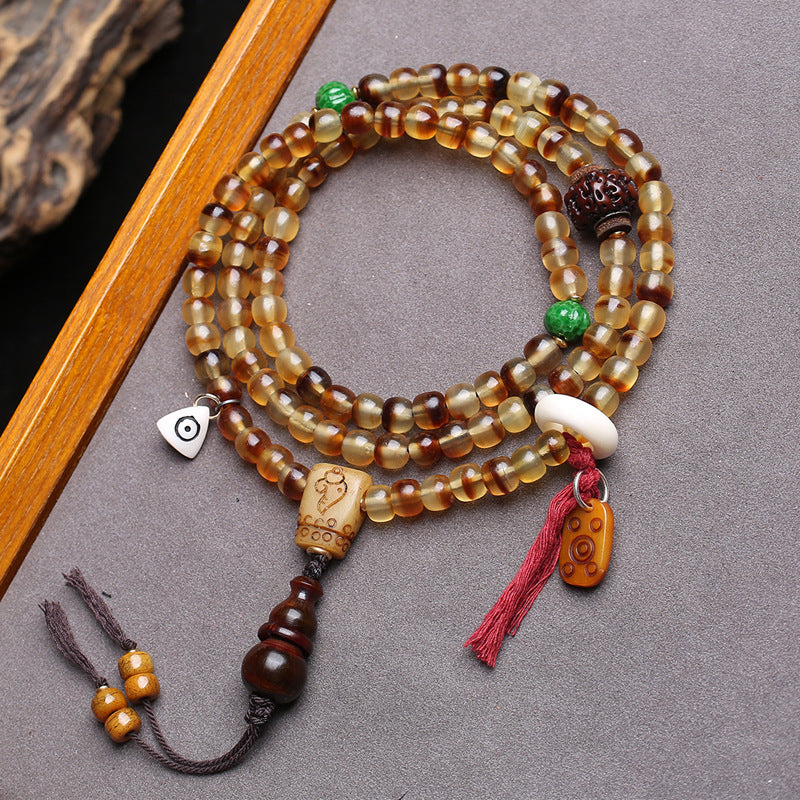 Golden turtle shell 108 mala coiled on grey surface showing full layout with all charms