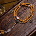Vintage crescent star bodhi 108 mala coiled on dark wood surface showing dzi stone and agate charms