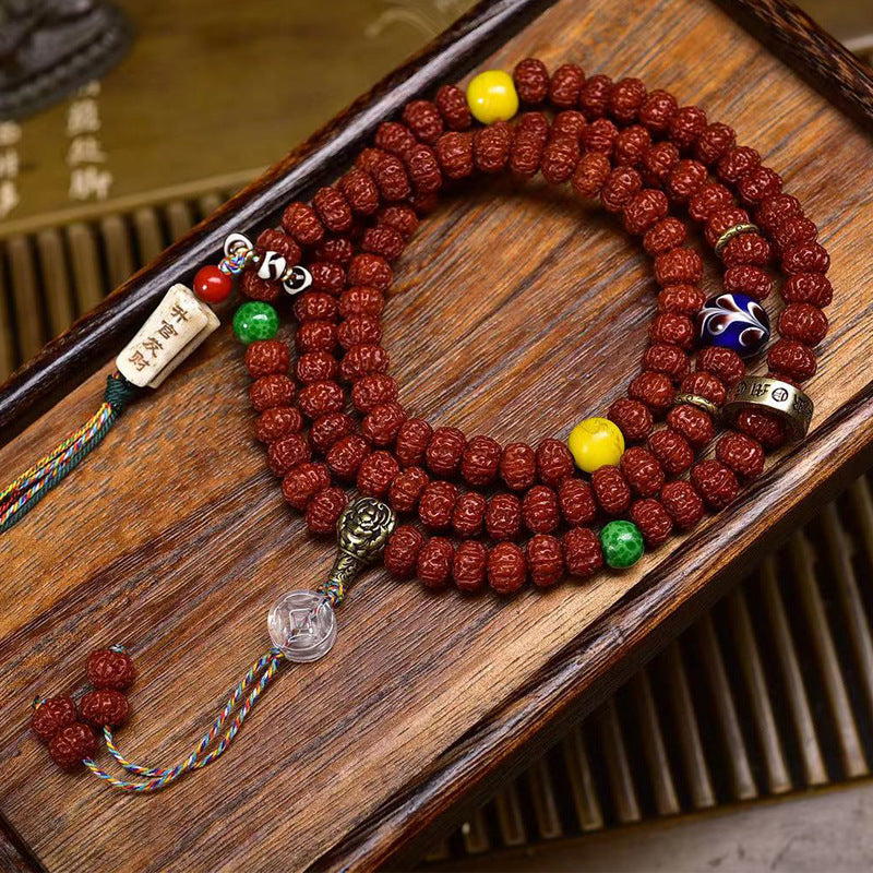 Vintage double dragon rudraksha 108 mala laid flat on wooden tray with colorful charms