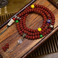 Vintage double dragon rudraksha 108 mala laid flat on wooden tray with colorful charms