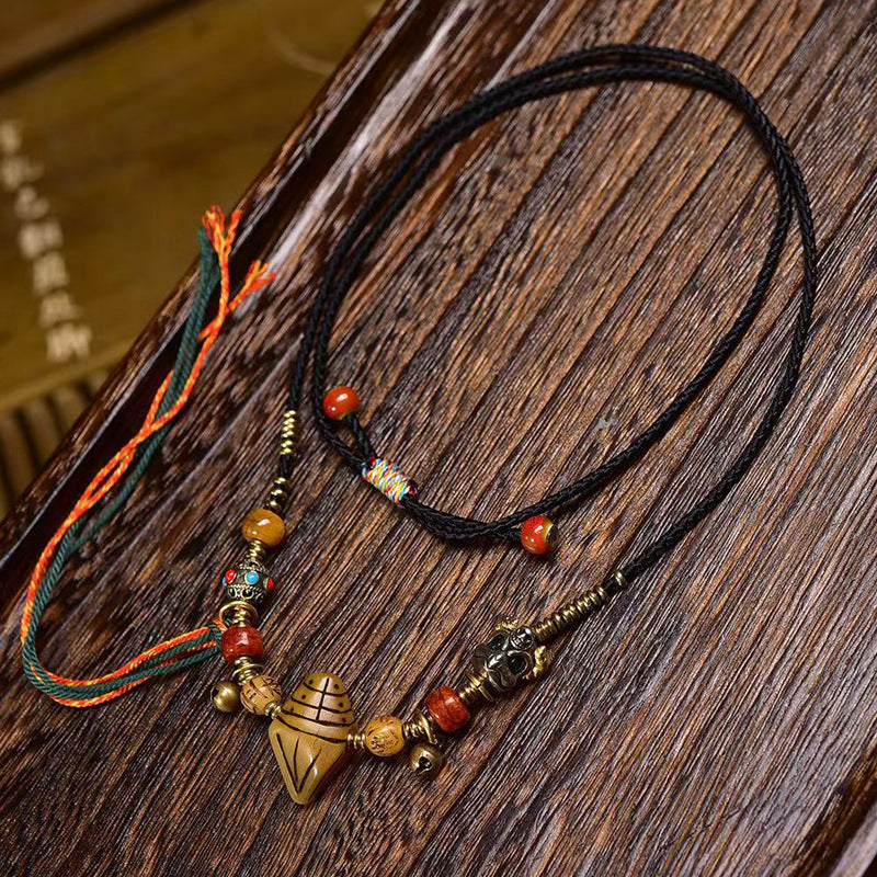 Close-up of beaded necklace with brass Garuda charm and bells