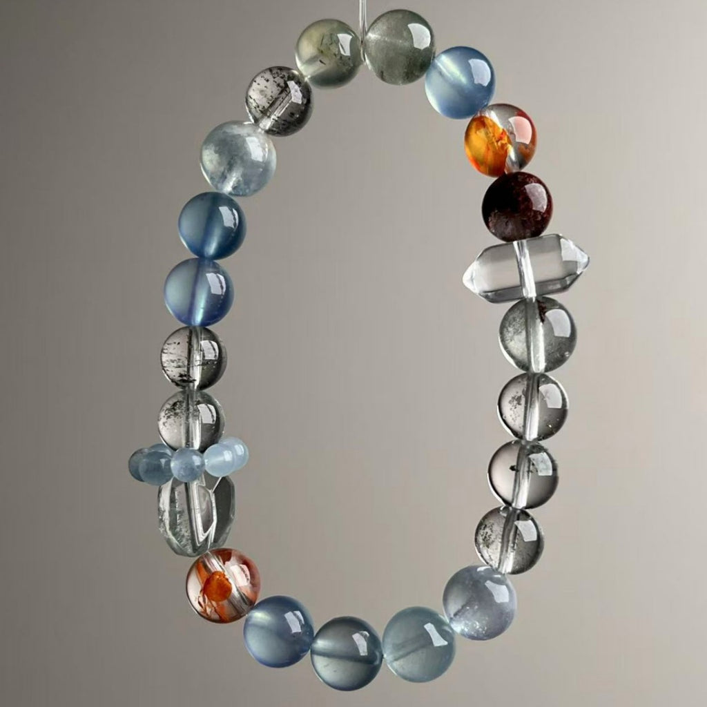 Brazilian mixed crystal bracelet with 9.5mm aquamarine, green phantom, red flower and clear quartz beads held in hand