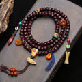 Jade-patina rudraksha 108 mala coiled on stone surface showing full layout with all charms