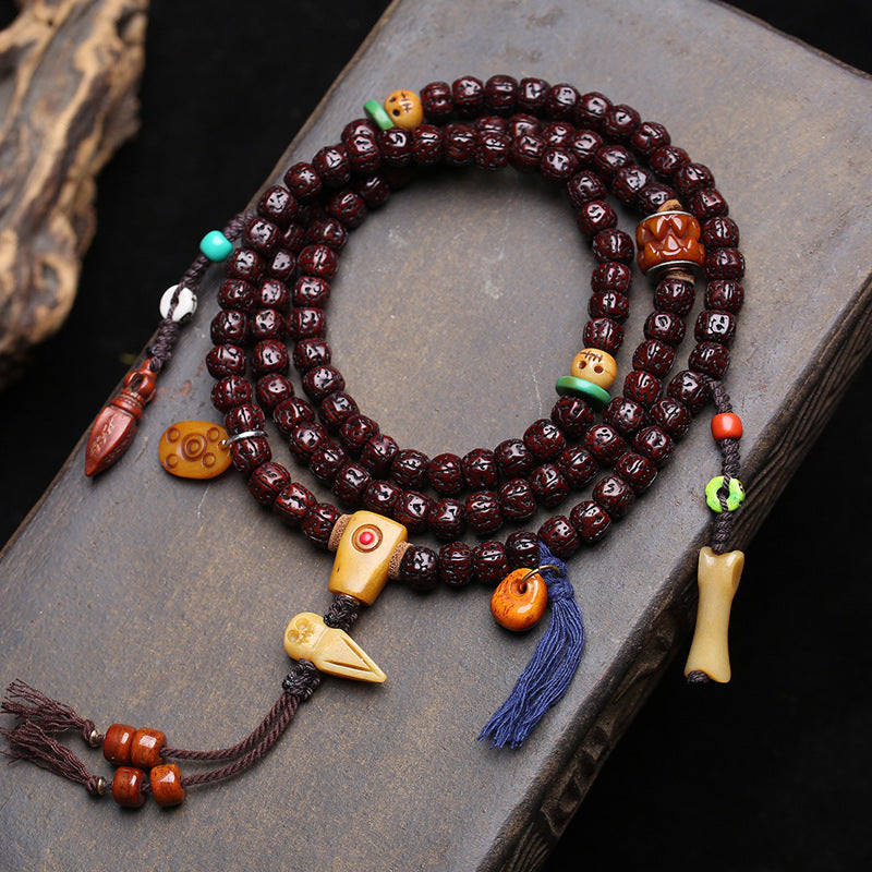 Jade-patina rudraksha 108 mala coiled on stone surface showing full layout with all charms
