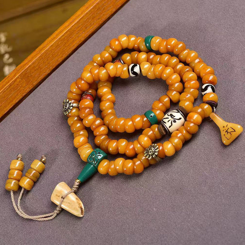 Tibetan yak bone disc mala coiled on grey surface showing full layout
