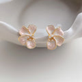 Pink enamel flower stud earrings on white ceramic dish