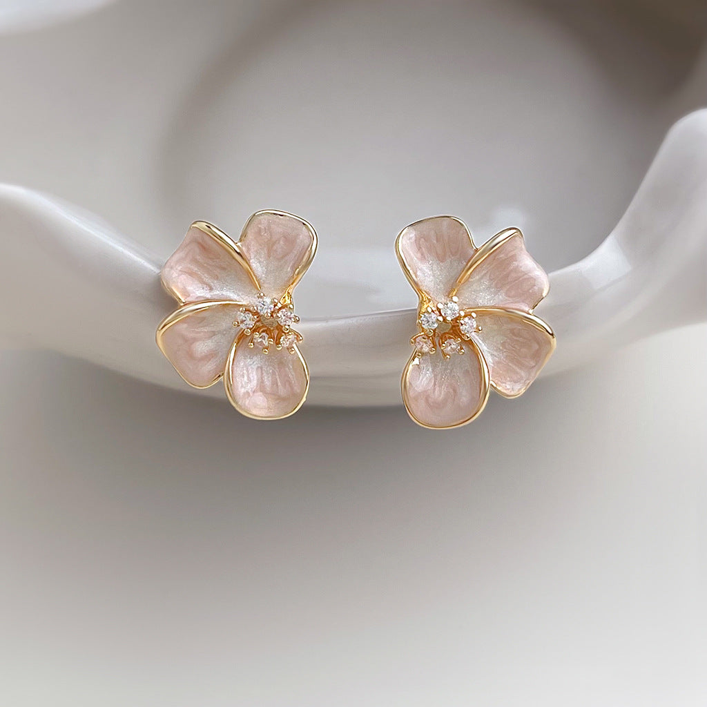 Pink enamel flower stud earrings on white ceramic dish