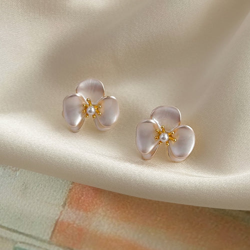 Phalaenopsis flower stud earrings with pearl center beside linen pouch