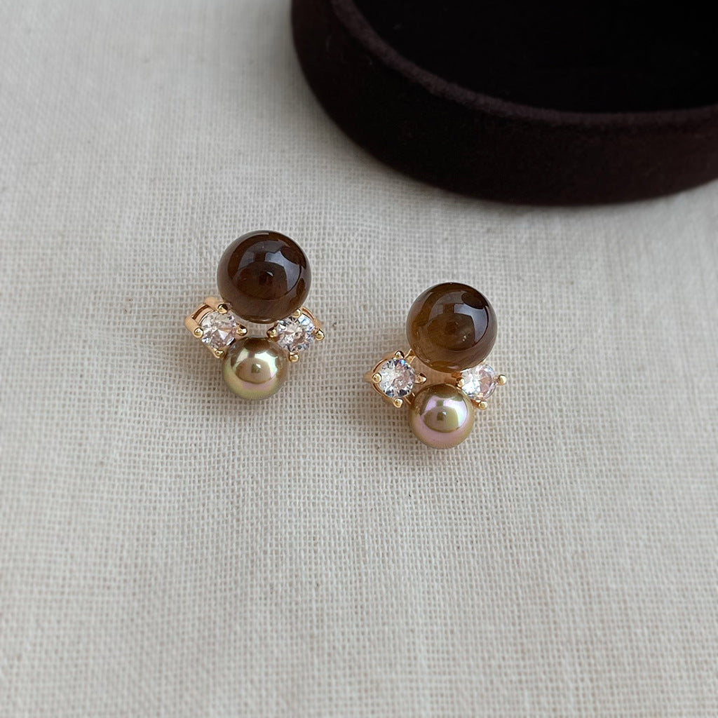 Tiger's eye and pearl stud earrings on grey knit fabric