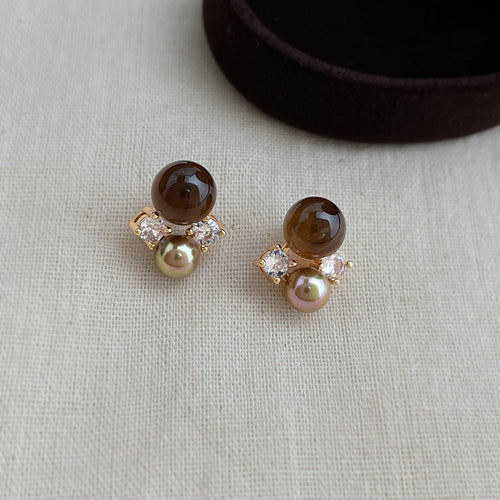 Tiger's eye and pearl stud earrings on grey knit fabric