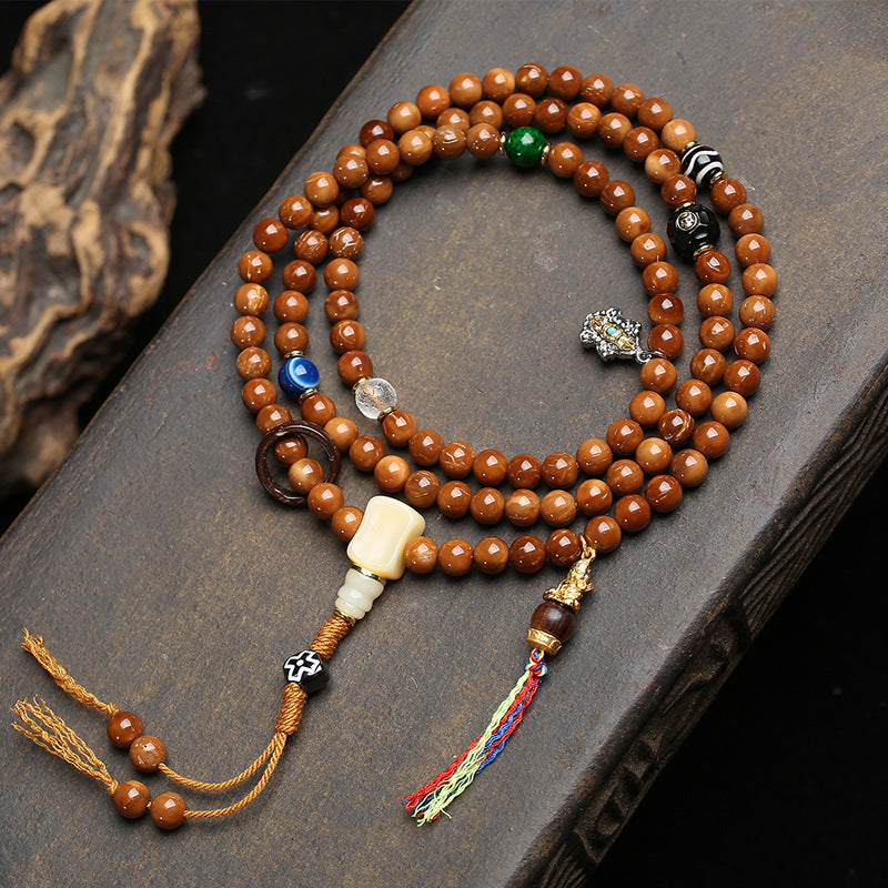 Close-up of cook seed mala guru bead and dzi stone charm