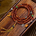 Vintage yak bone 108 mala on grey surface with bone ring guru bead, red agate and colorful tassel