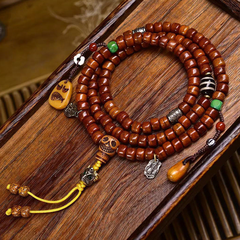 Vintage yak bone 108 mala on grey surface with bone ring guru bead, red agate and colorful tassel