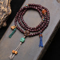 Vintage red sandalwood 108 mala laid flat on stone surface with skull guru bead and colorful tassels