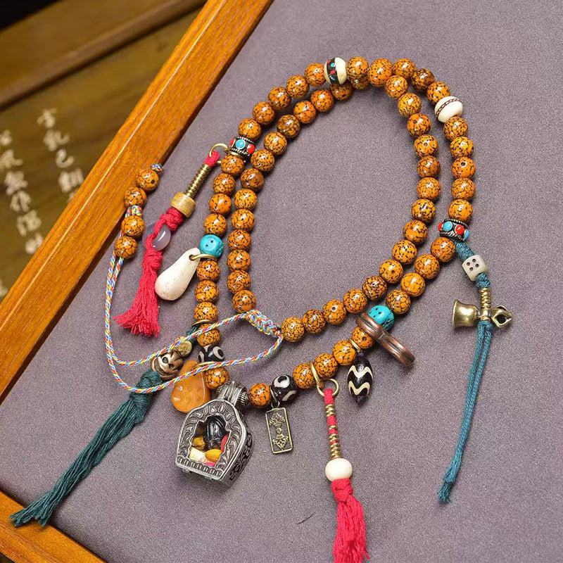 Tibetan star moon bodhi mala flat lay with gau box and charms