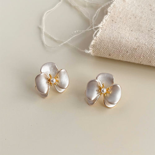 Pearlescent orchid stud earrings on cream satin