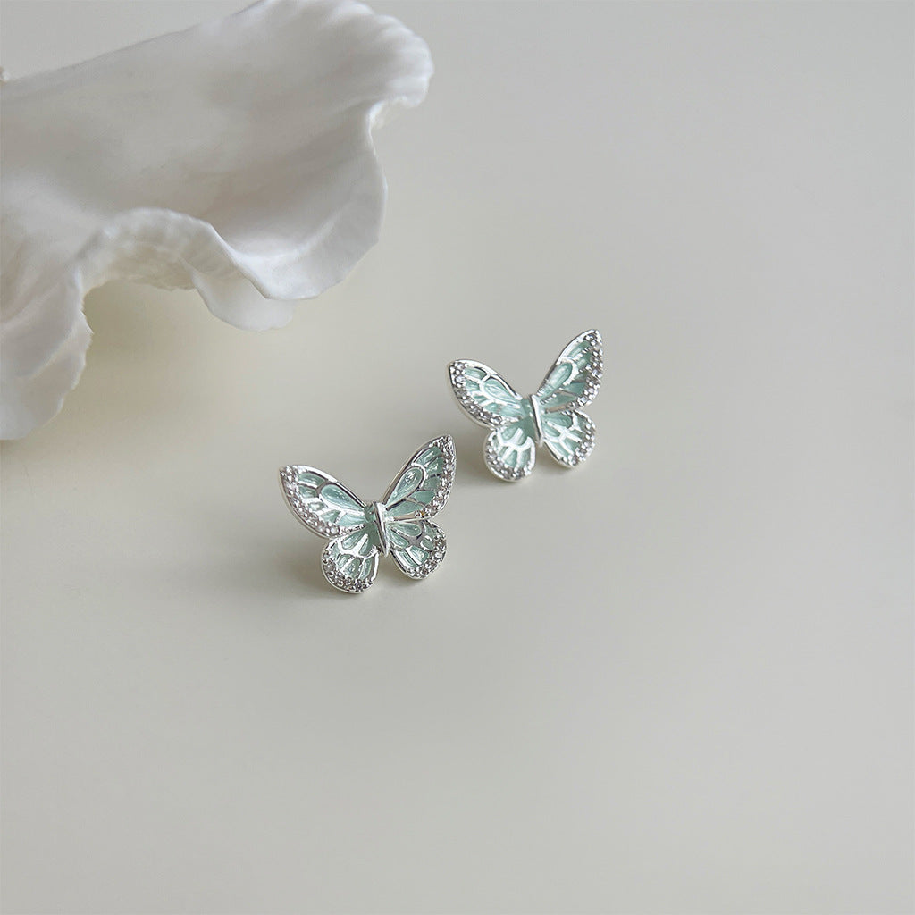 Butterfly stud earrings with zircon edges beside pearls