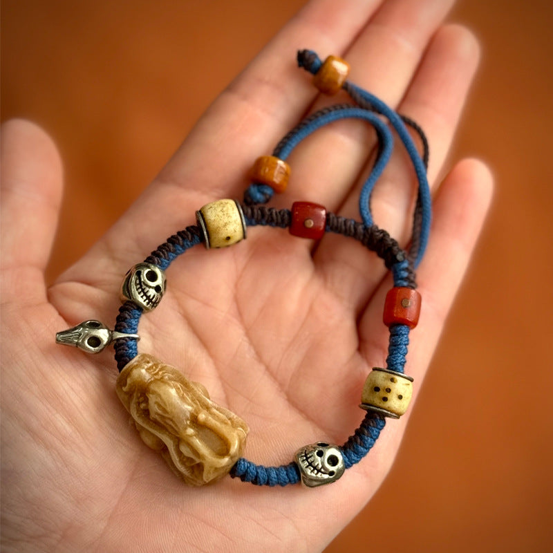 Tibetan bone bracelet with Pixiu carving and skull beads on blue cord