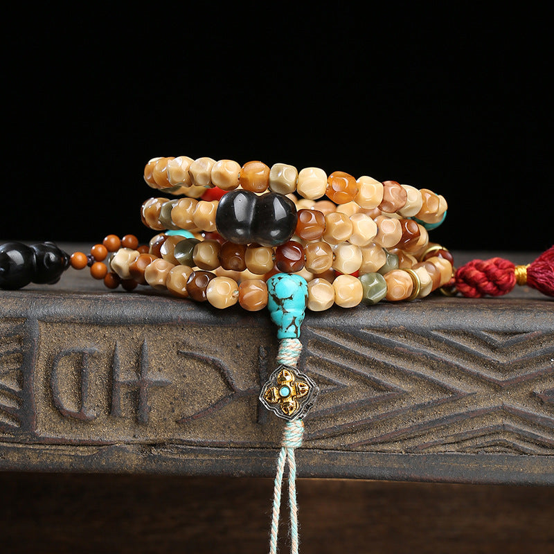 Dragon spine bodhi mala wrapped as multi-layer bracelet on carved wooden box showing turquoise guru bead