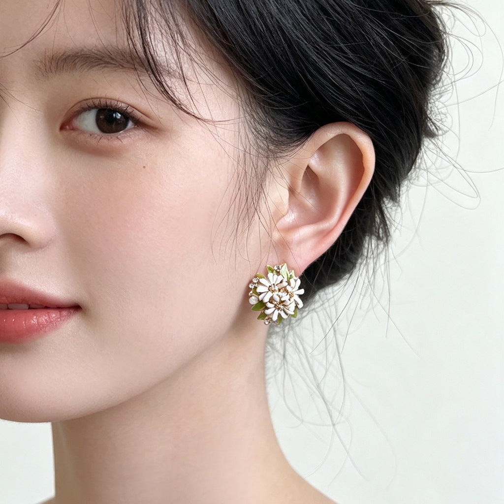Enamel daisy flower stud earrings on white ceramic dish
