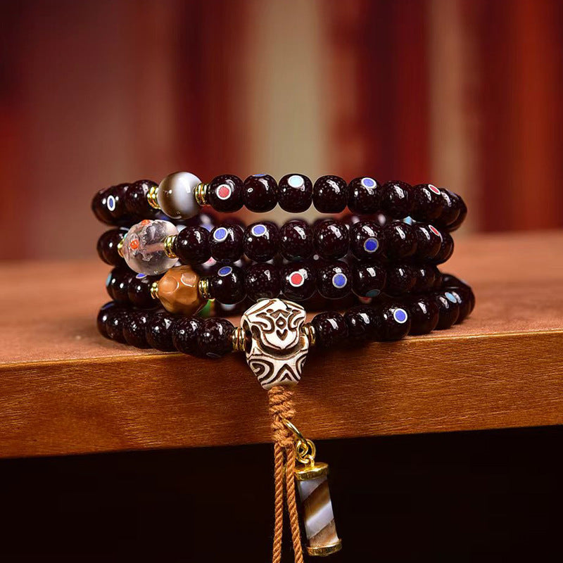 Cinnabar bodhi mala wrapped as multi-layer bracelet on wooden stand showing bone guru bead and agate pendant