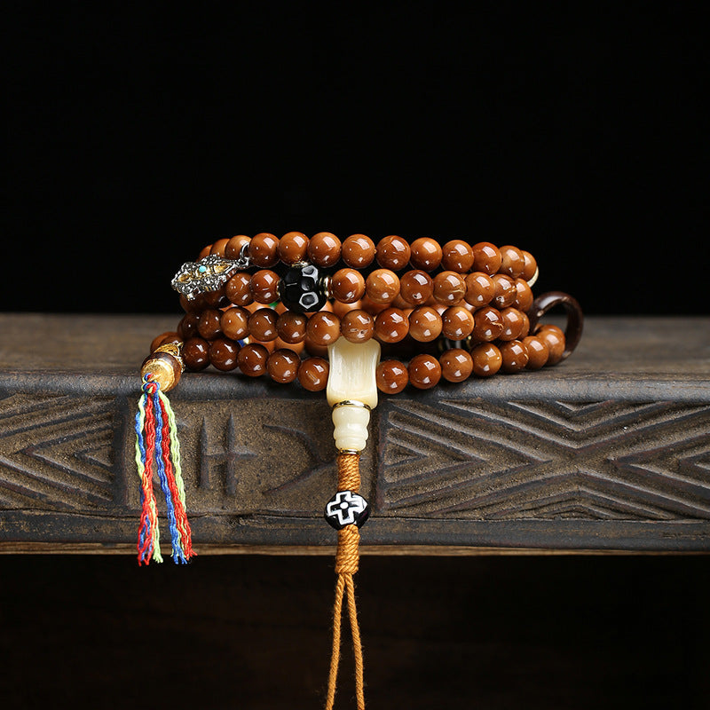 Cook seed mala wrapped as multi-layer bracelet on wooden surface
