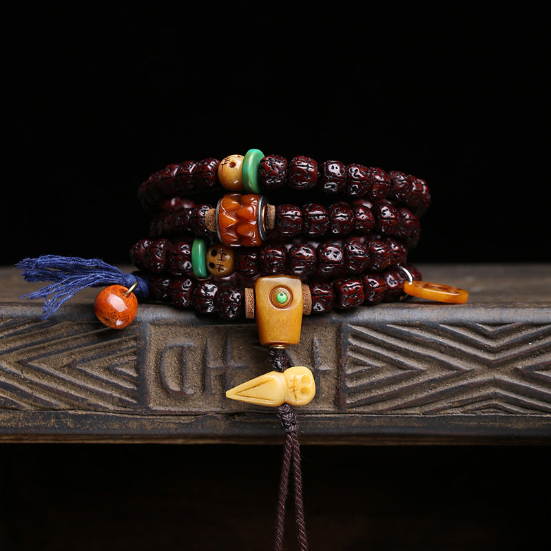 Rudraksha mala wrapped as multi-loop bracelet on carved wooden stand showing bone A-Dai pendant