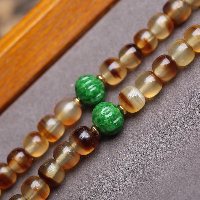 Close-up of amber gradient turtle shell barrel beads and green glass spacers
