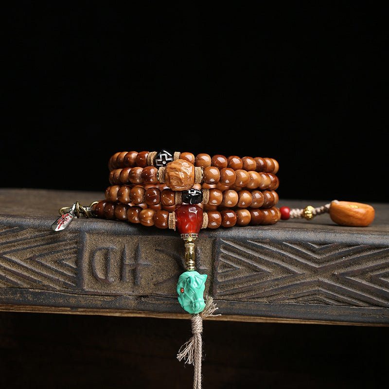 Cocos mala wrapped as multi-loop bracelet on wooden tray with turquoise horse head and red agate charm