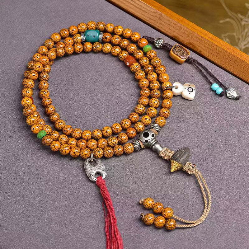 Cracked star moon bodhi mala laid flat on grey surface showing full length with silver guru bead and red tassel