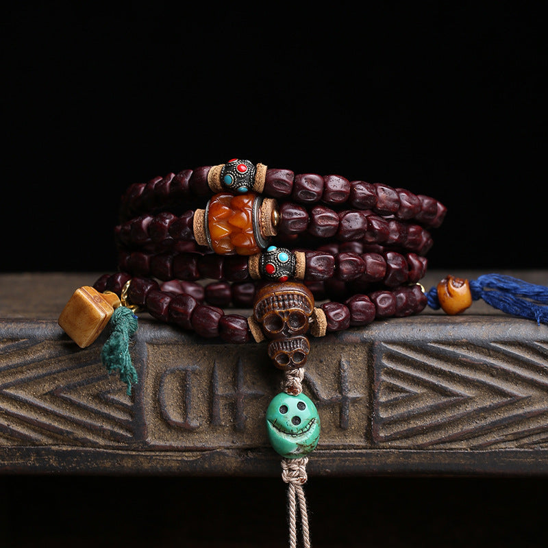 Red sandalwood mala wrapped as multi-loop bracelet on wooden tray showing amber and turquoise charms