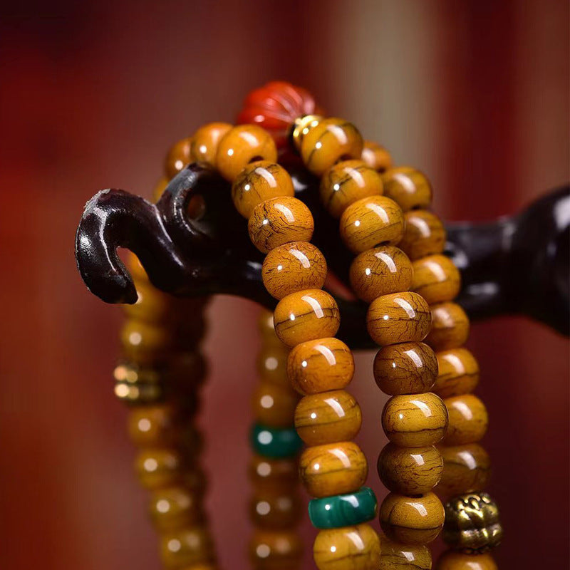 Close-up of warm honey yak bone disc beads with turquoise spacers and gold brass charm