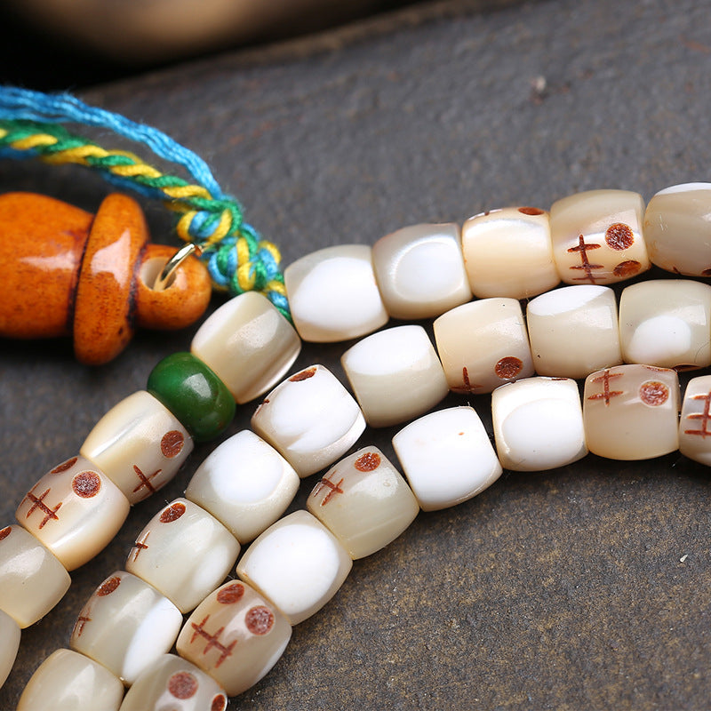 Close-up of fish bone Ah-Dai skull barrel beads with green jade spacer and colorful tassel