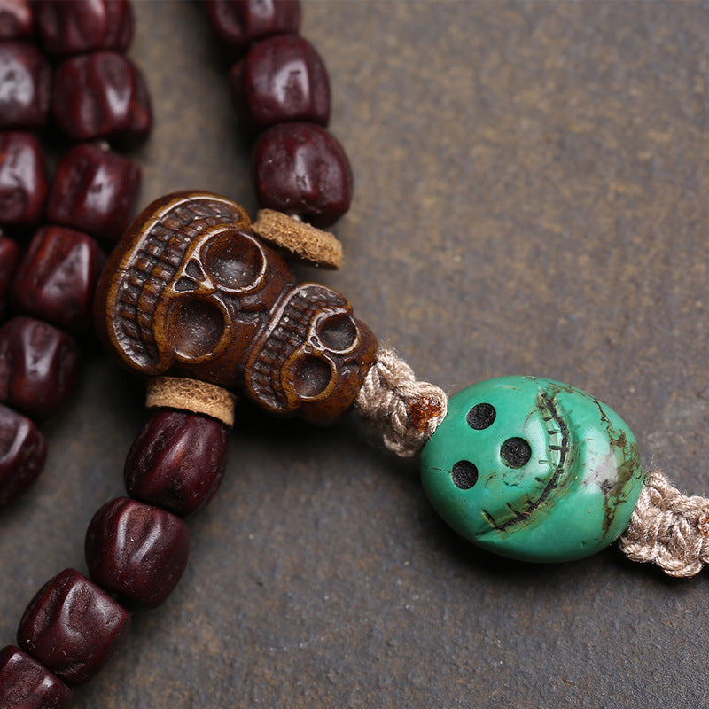 Close-up of skull guru bead and turquoise skull pendant on red sandalwood mala