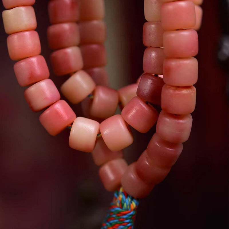 Close-up of half-red yak bone barrel beads showing natural gradient color and silky matte finish
