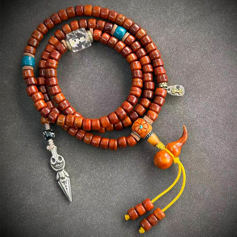 Yak bone mala on grey surface with Mahakala medallion pendant, skull spacer and colorful tassel