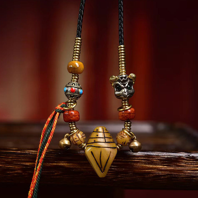 Carved talisman pendant with amber and red beads and brass bells