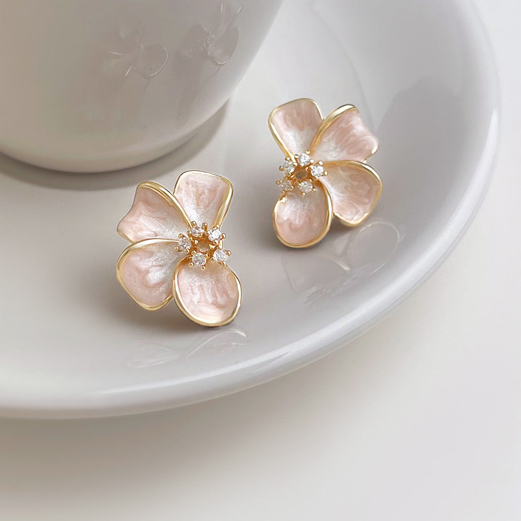 Gold plated pink flower stud earrings on saucer