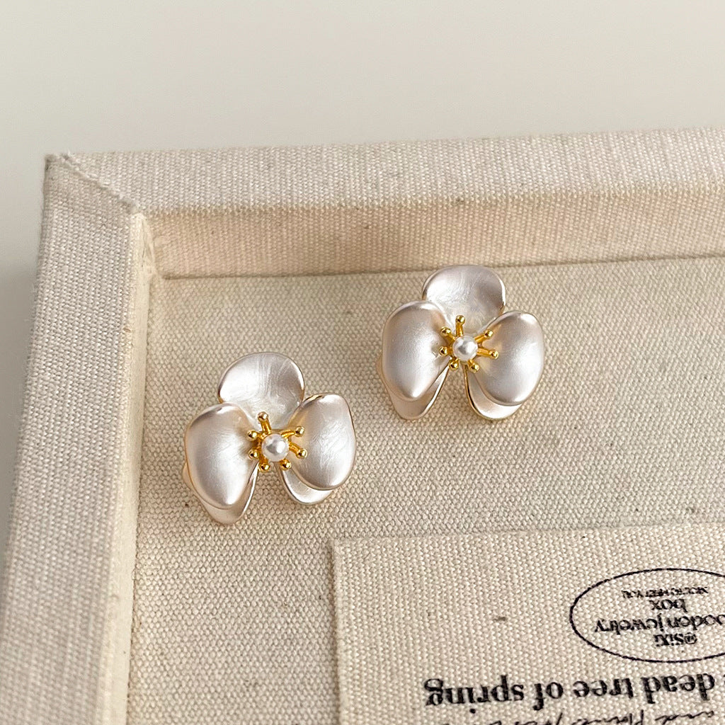 Gold plated orchid flower earrings on linen jewelry tray