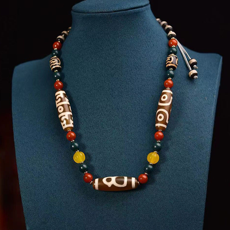 Agate dzi bead necklace with red, green and yellow beads on wood