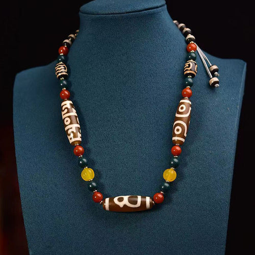 Agate dzi bead necklace with red, green and yellow beads on wood