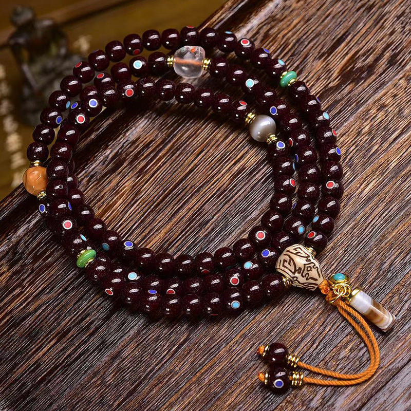 Full cinnabar star moon bodhi mala laid flat on dark wood showing colorful eye inlays and tassels