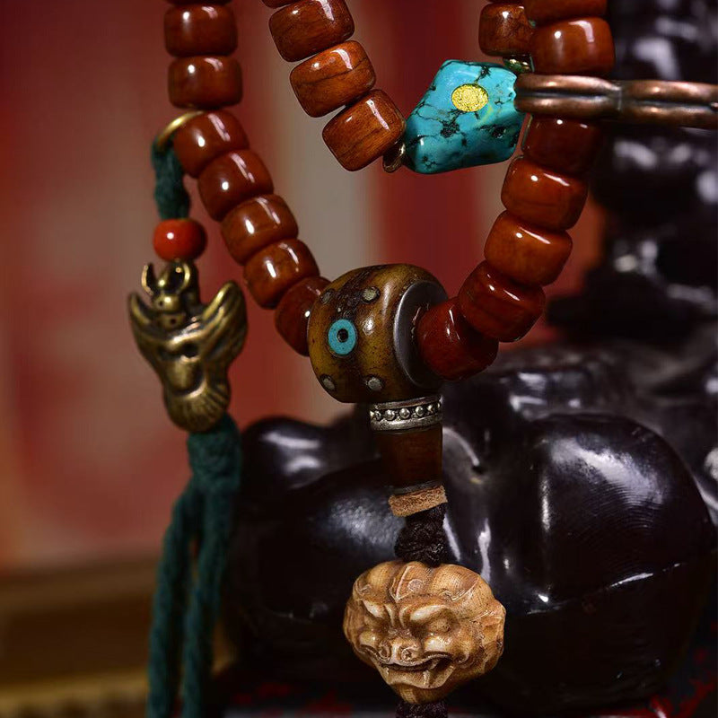 Close-up of Tibetan mala guru bead with turquoise and Nara Sakya charm on figurine