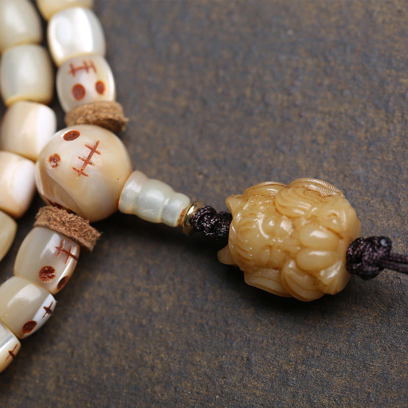 Close-up of hand-carved bone nine-tailed fox pendant with gold cap on fish bone mala